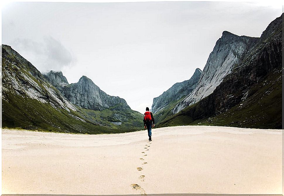 Traveler walking between mountains to de-stress, another reason why we travel